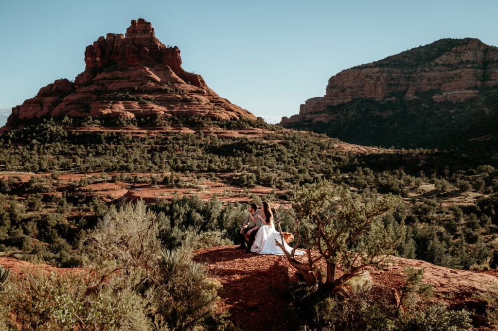 Wedding couple sitting on a red rock looking at the views of Bell Rock during their Sedona elopement