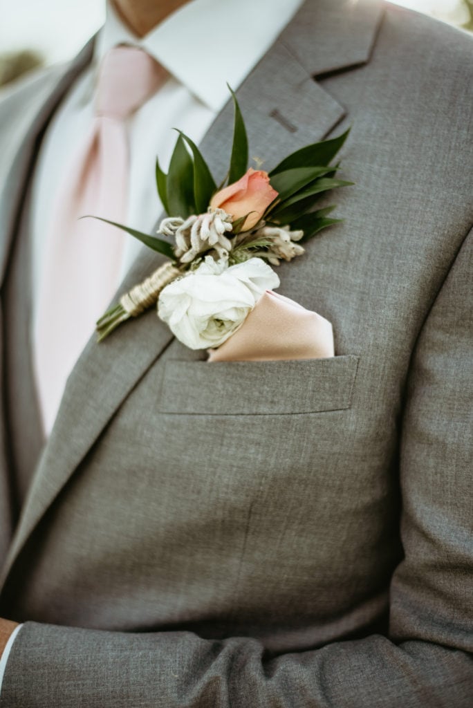 Light pink rose boutonniere on a grey tux
