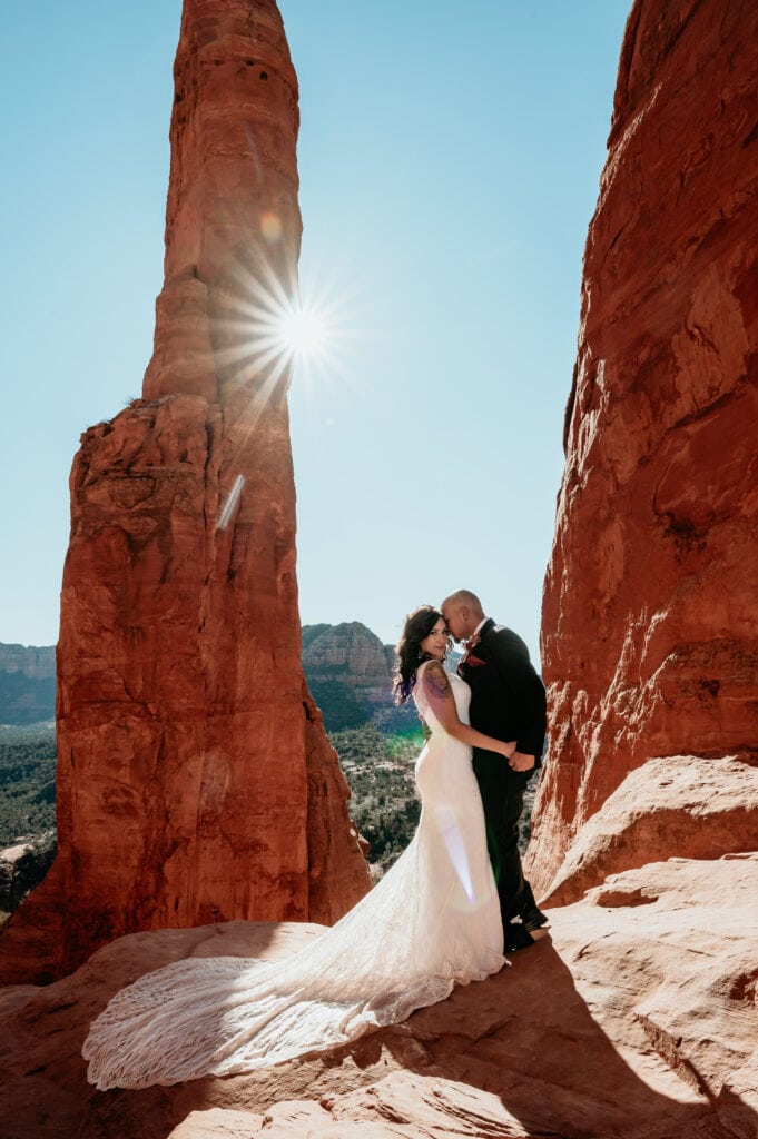 Bride and Groom embrace as the sun rises behind a giant red rock spire on their wedding day