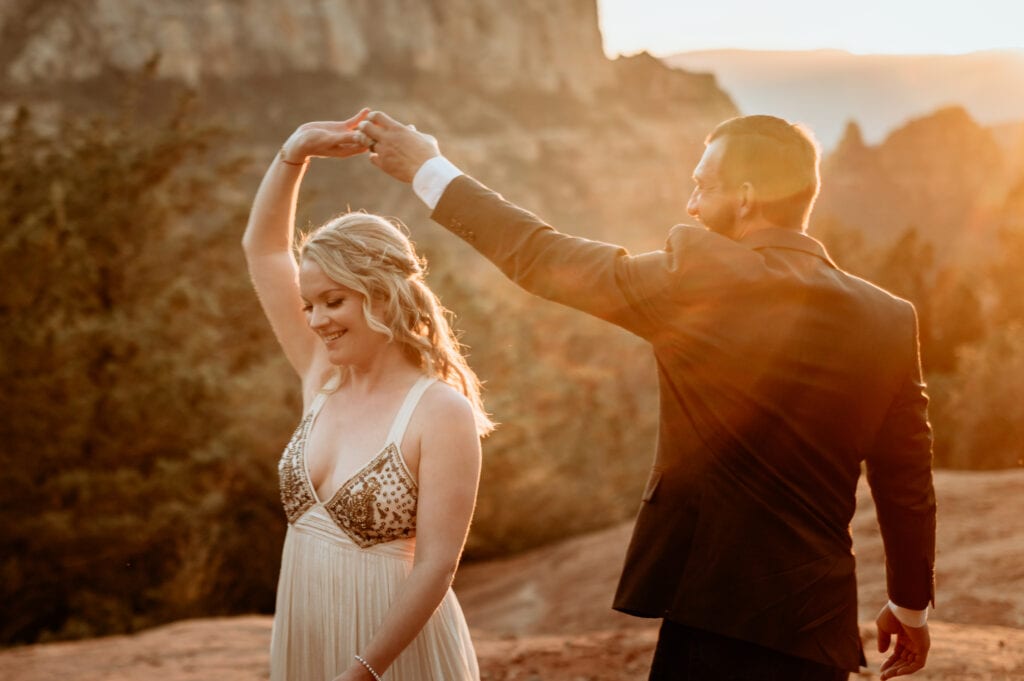 Golden light washing over bride and groom during their first dance in the Sedona red rocks for their wedding day