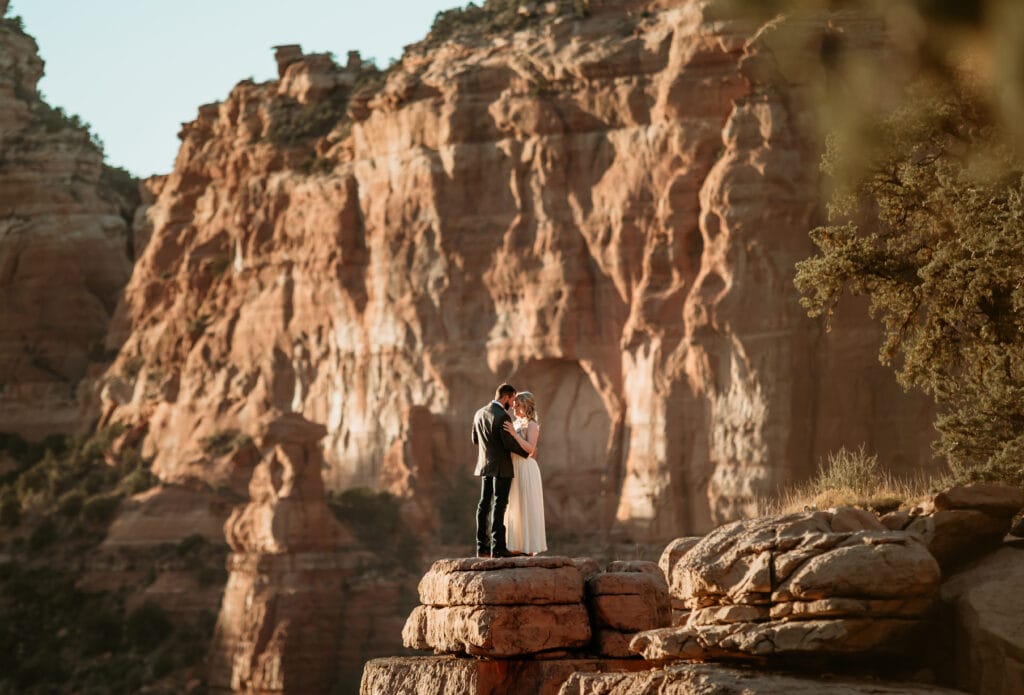 Eloping couple standing on a pedestal at Merry Go Round Rock in Sedona Arizona