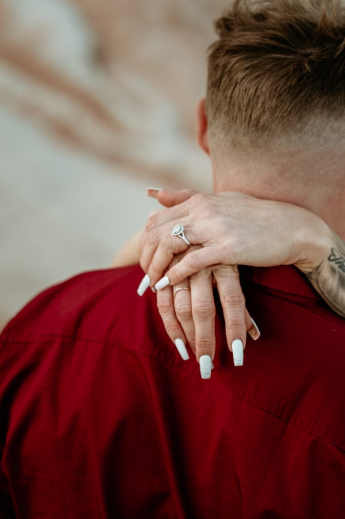 Engagement ring on hands draped over neck
