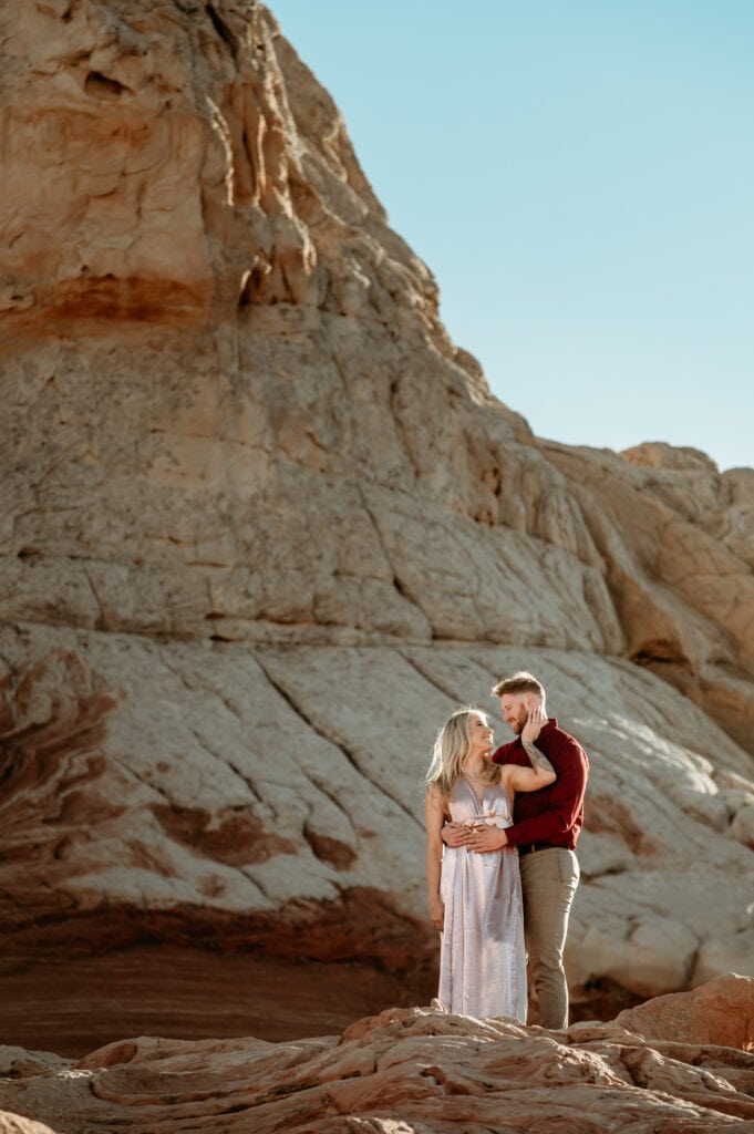 Nick embraces Cassie from behind surrounded by Vermillion Cliffs red and white sandstone formations