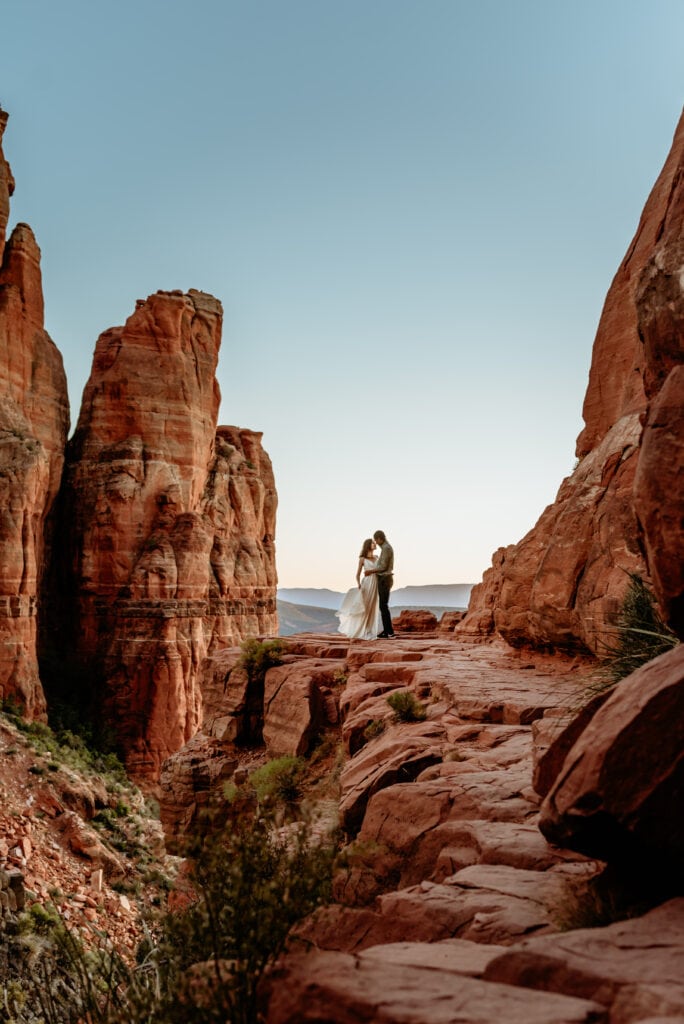 A dramatic kiss at the peak of Cathedral Rock in Sedona, Arizona by a sweet elopement couple taken by Arizona Elopement Photographer Shannon Durazo who hikes with couples to take epic photographs