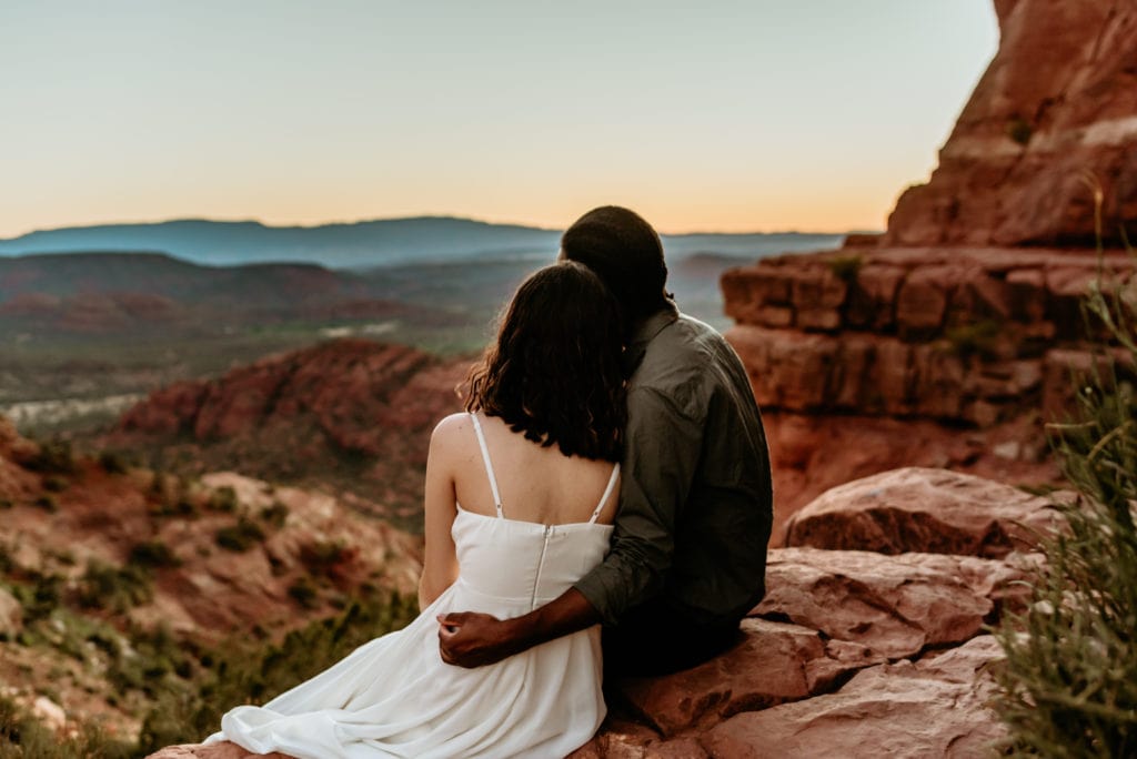 Couple relaxes and watches the sunset over Sedona on their Cathedral Rock elopement