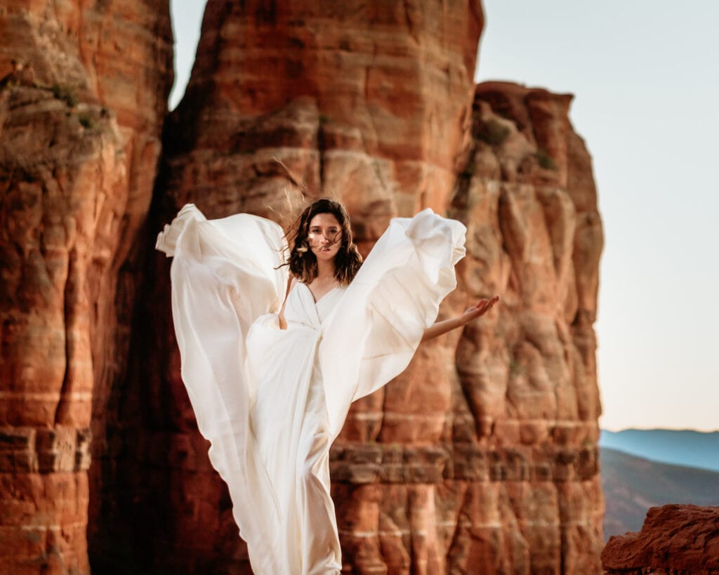 Bride with flowing dress at the ledge of Cathedral Rock trail