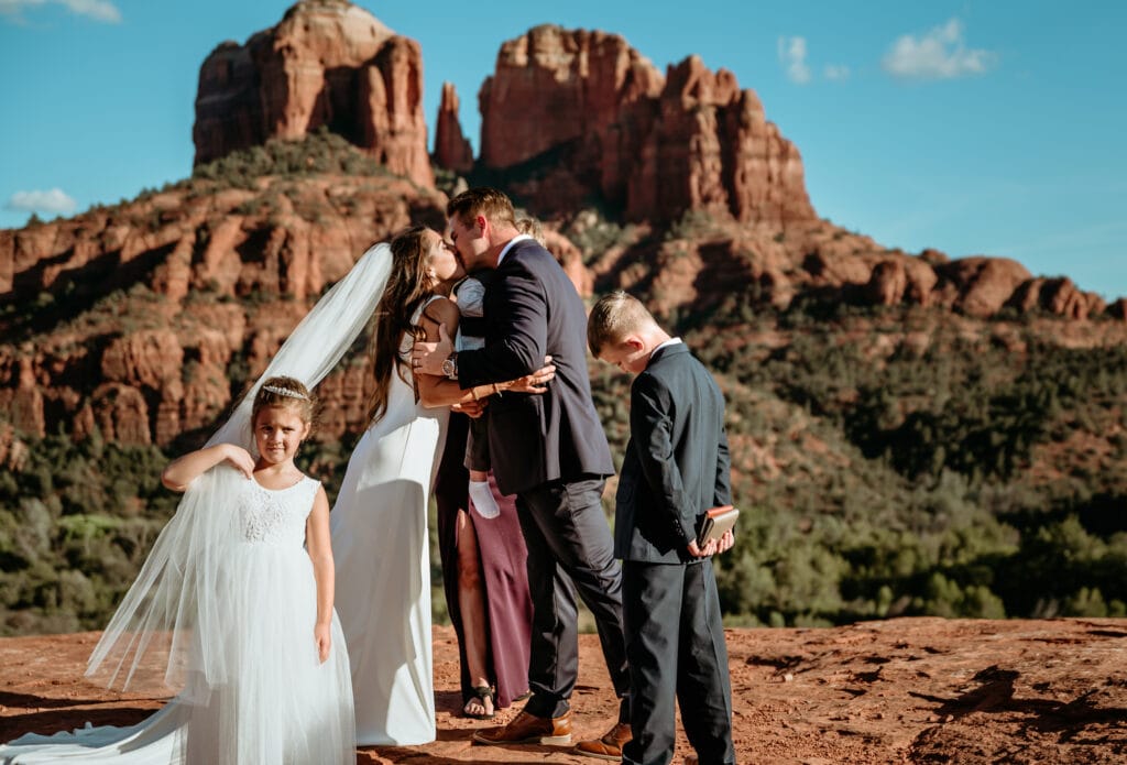 Eloping couple's first kiss surrounded by their children in the red rocks of Sedona, AZ
