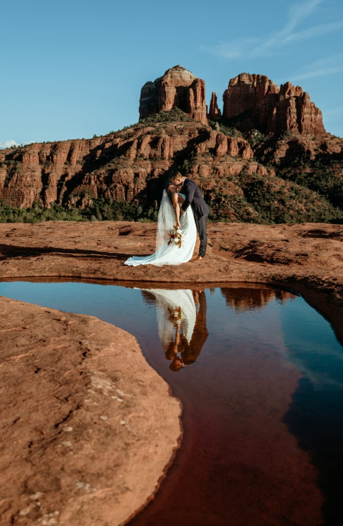 Bride and groom kiss with their reflection in a puddle during Sedona elopement