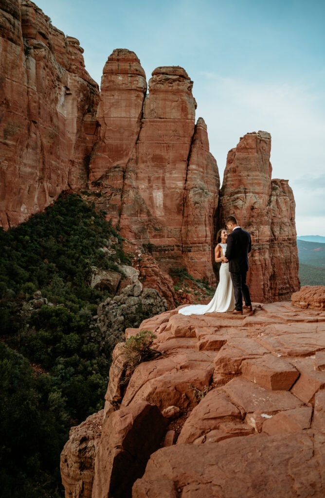 Couple on the edge of the Cathedral Rock ledge during their sunrise elopement
