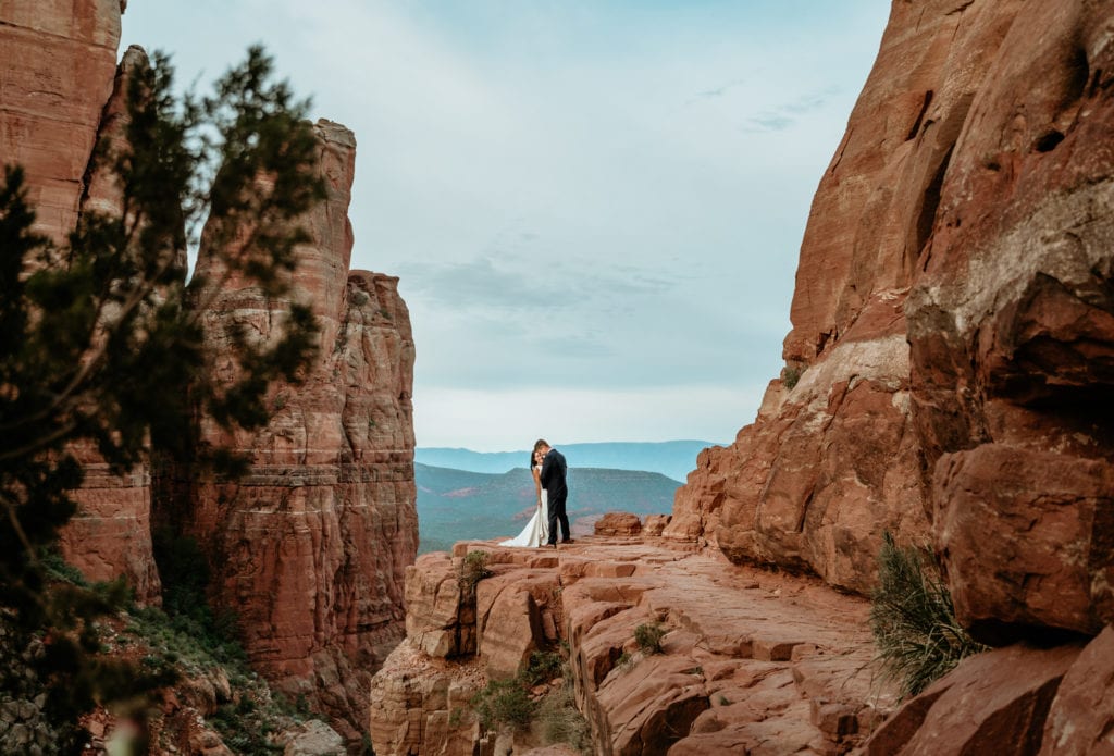 Bride and groom on the ledge of Cathedral Rock during while the elope in Sedona