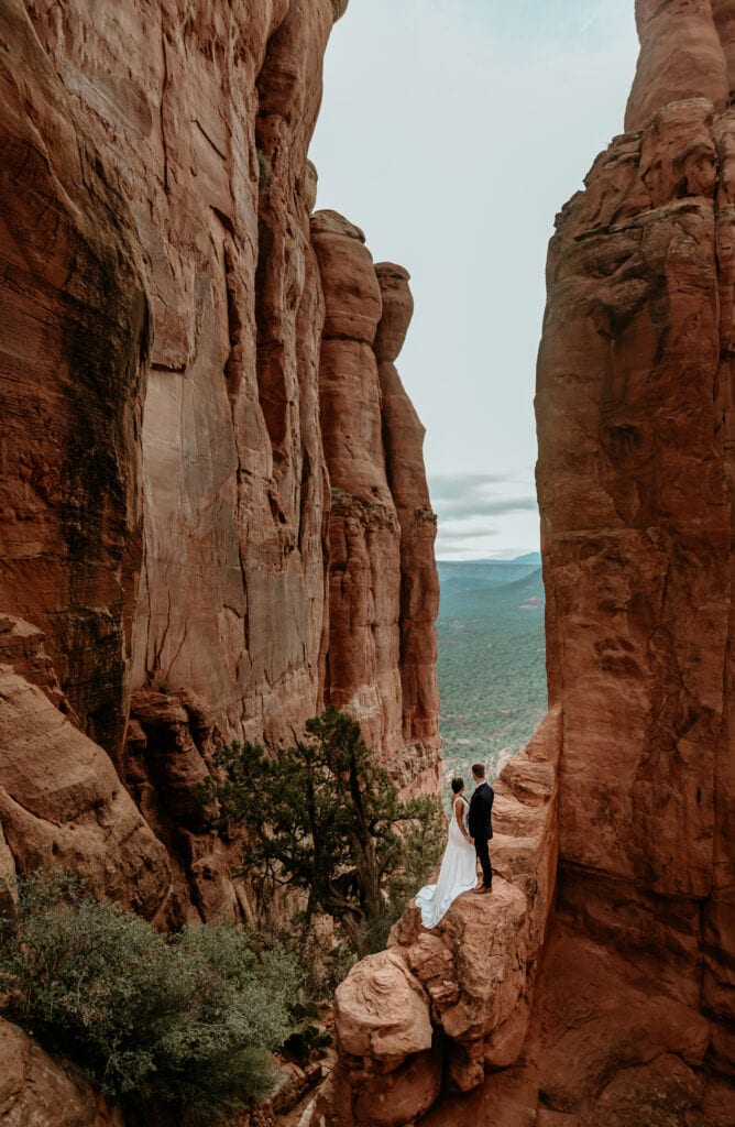Adventurous couple standing on ledge during their Sedona elopement by Sedona elopement photographer Shannon Durazo
