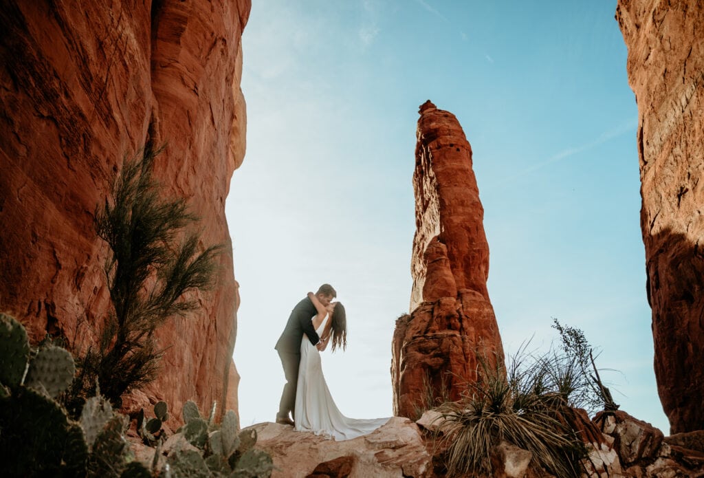 Cathedral Rock elopement couple embrace as the sun rises behind the spire