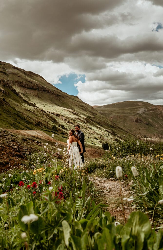 Elopement couple walking through summer wildflowers in the San Juan Mountains of Colorado