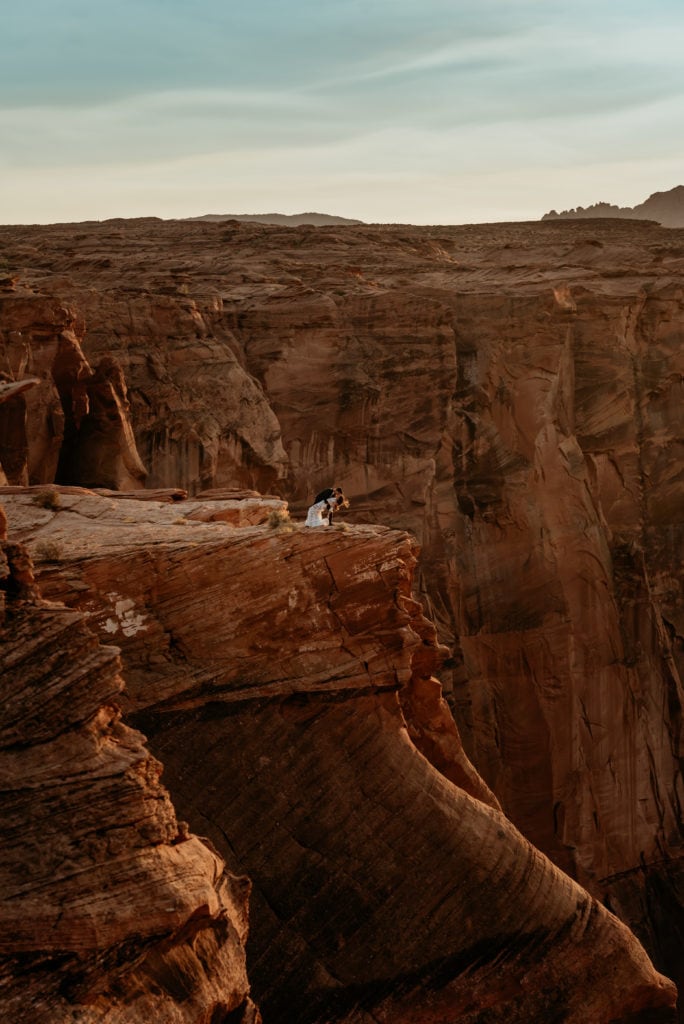 Groom dipping his bride on the ledge of Horseshoe Bend in Northern, Arizona