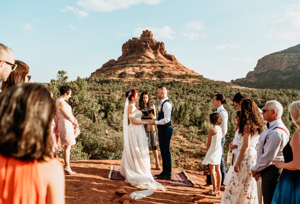 Sedona elopement framed by Bell Rock as bride and groom stand surrounded by their families