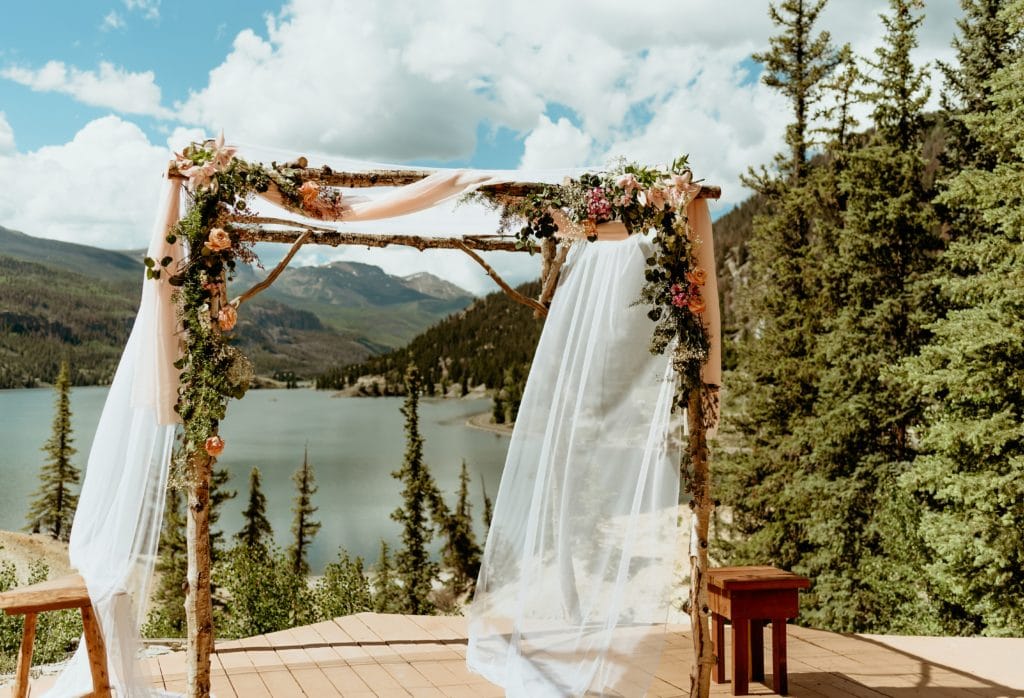 Aspen chuppah decorated with live flowers and flowy fabric overlooking Lake San Cristobal