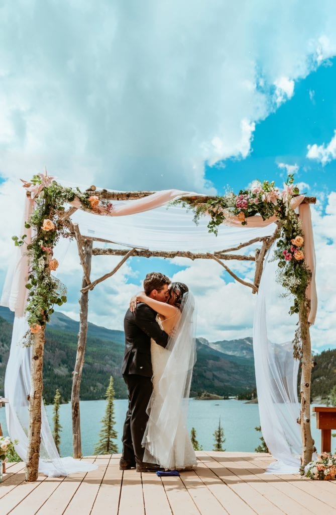 First kiss under an aspen chuppah overlooking Lake San Cristobal during Lake City, Colorado wedding