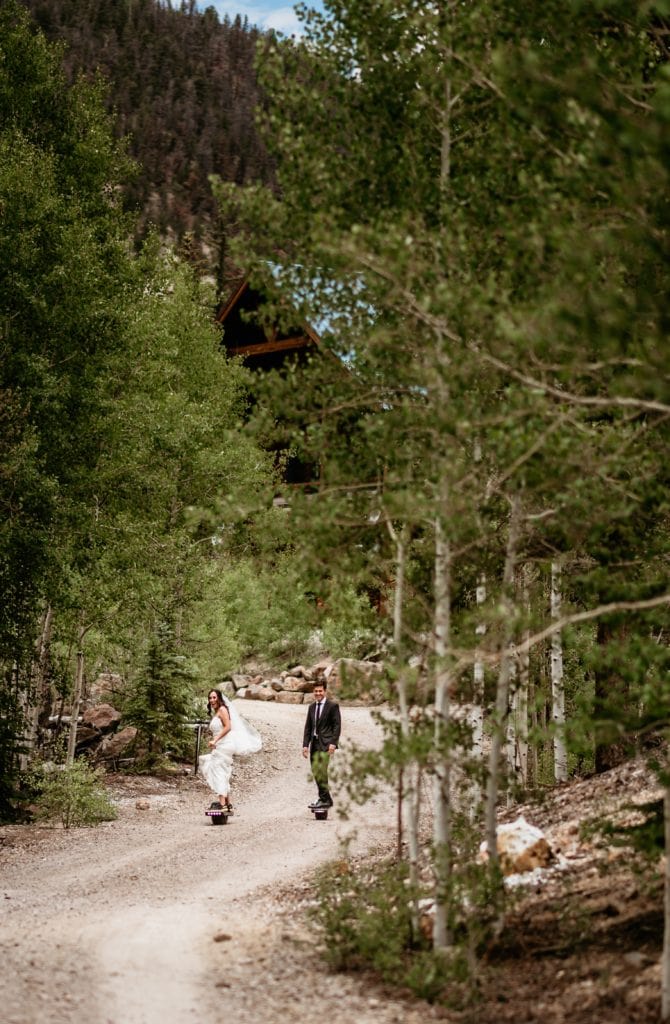 Bride and groom riding their one wheels up a gravel driveway in Colorado