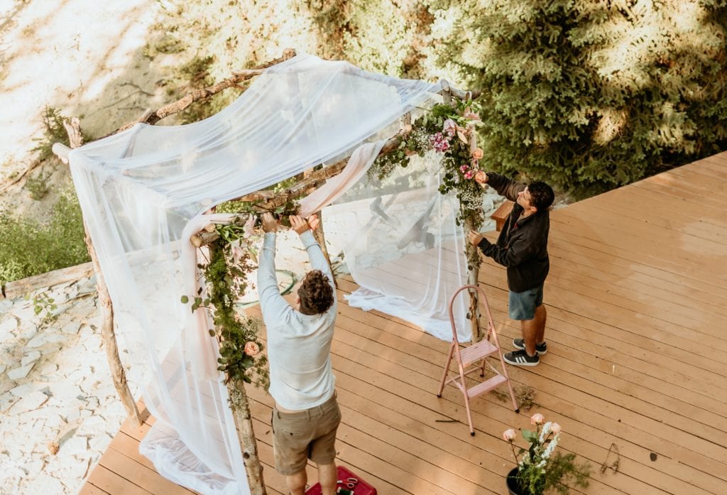 Groom and brother of the bride decorate the Chuppah with live florals
