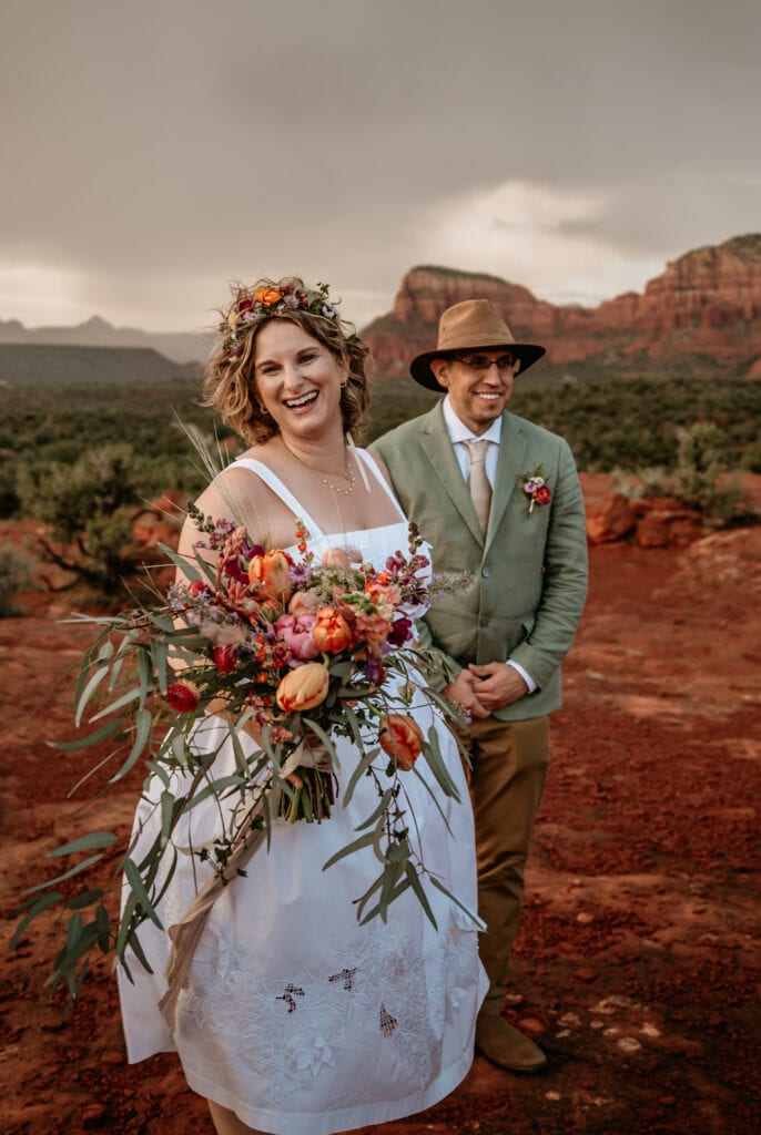 Laughing bride with a rainstorm in the distance captured by Sedona elopement photographer Shannon Durazo