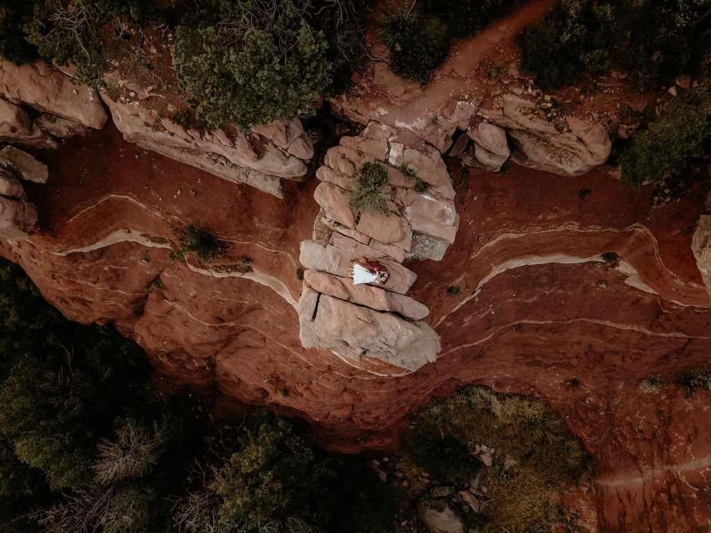 Drone shot of couple laying on a red rock ledge taken during their Sedona elopement