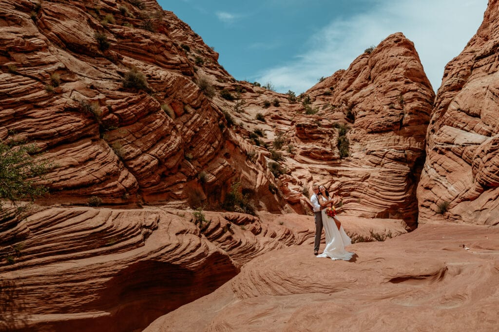Bride and groom laughing surrounded by etched red rock formation during their Arizona elopement