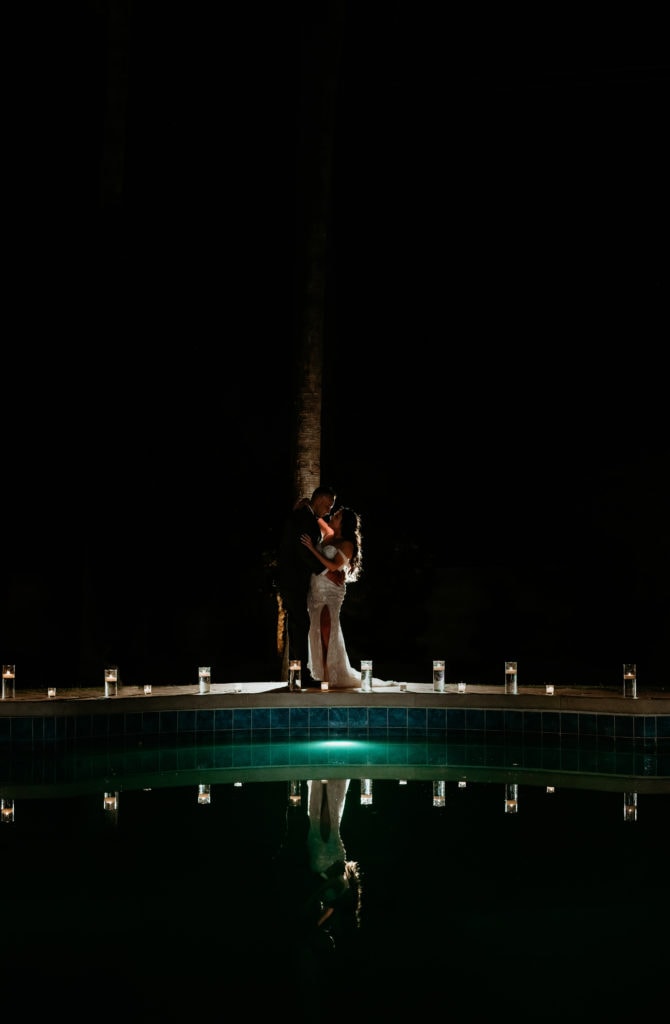 Bride and groom with nighttime reflection in pool
