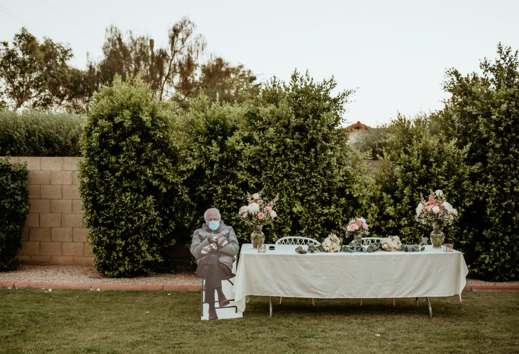 Funny Bernie in mittens cutout by the sweetheart table during backyard wedding