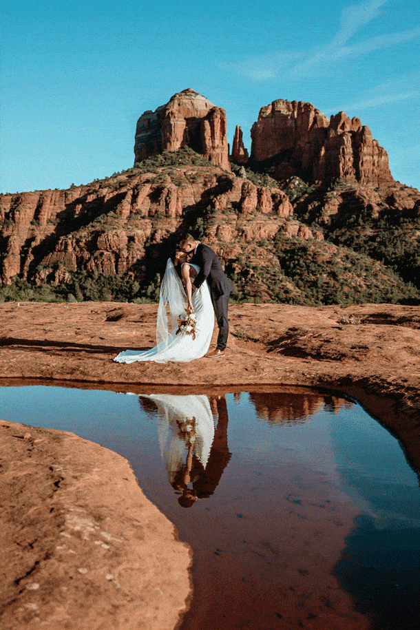 Bride and groom kissing at their Secret Slickrock elopement with reflection in a puddle and Cathedral Rock in the background