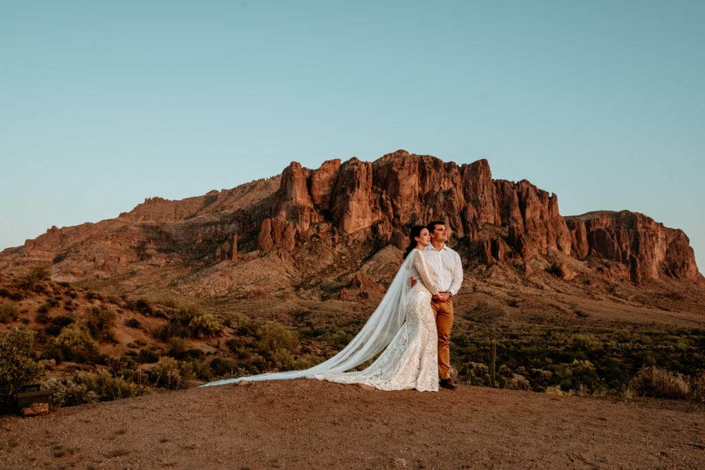 Elopement couple watching the sunset as the Superstition Mountains glow behind them