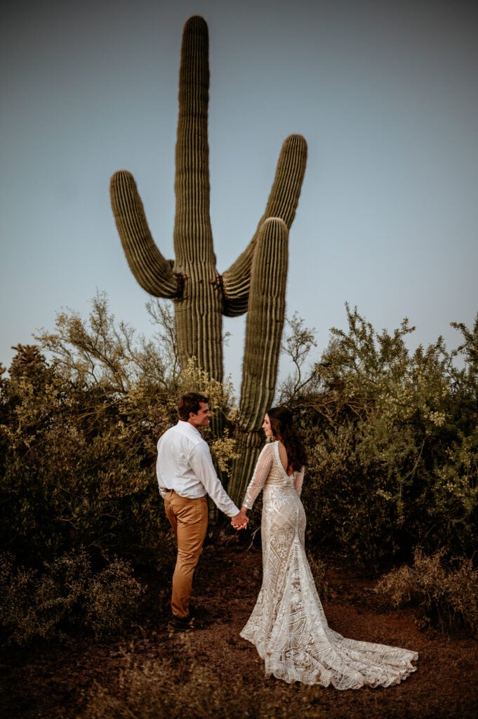 Elopement Couple standing by giant saguaro in the Arizona desert during their elopement