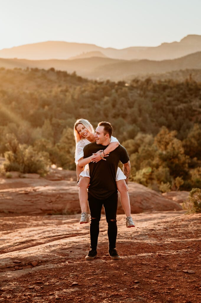 couple on their  Sedona engagement session giving a piggy back ride