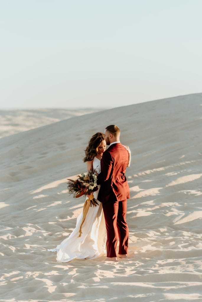 Couple embraces at their sand dune wedding