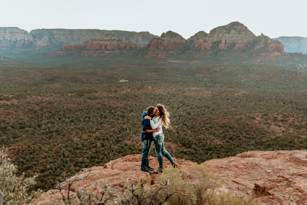 couple embraces in a kiss at the top of their romantic hike in Sedona AZ