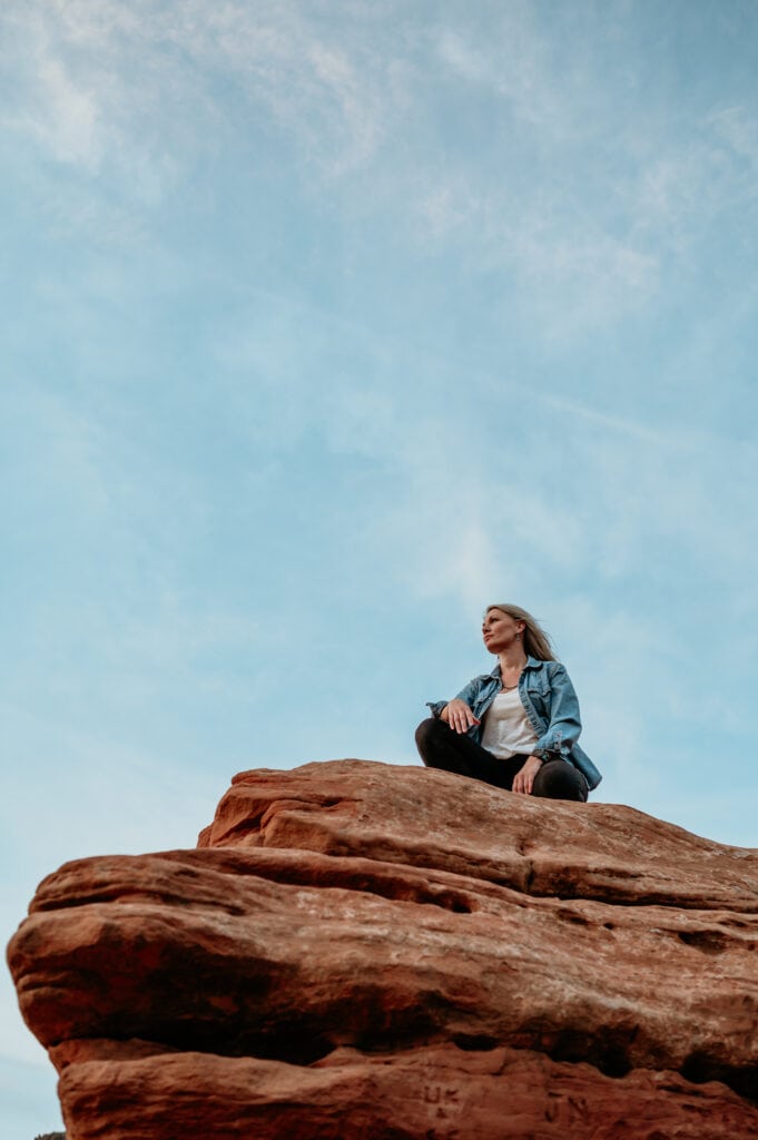 Shannon durazo of Stratus Adventure Photography crouched on top of a red rock boulder in Sedona Arizona