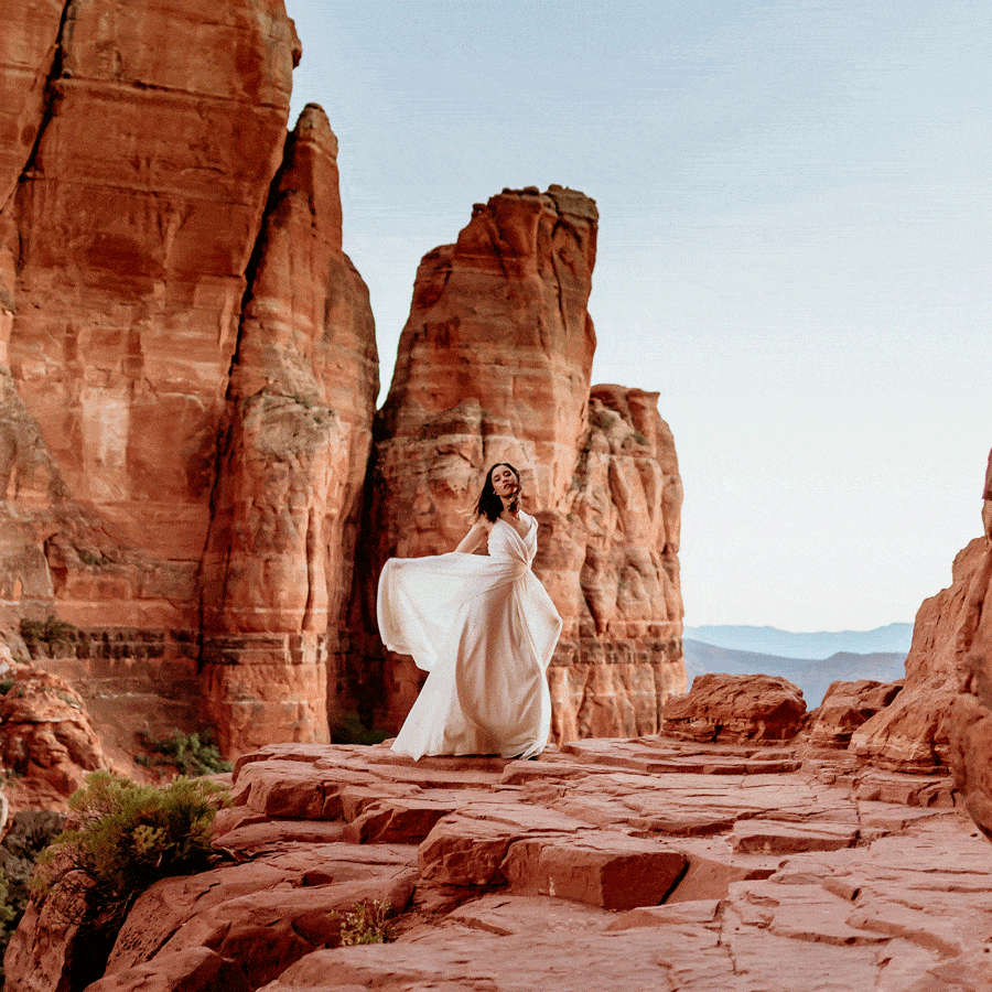 Bride's dress flowing in the wind as she looks like an angel on the highest ledge of Cathedral Rock